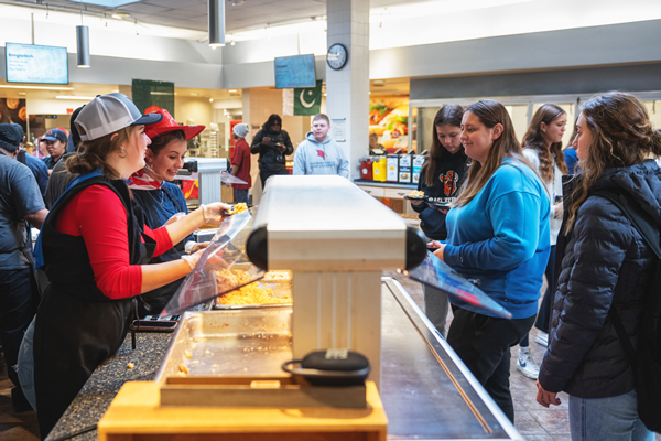 Dining staff serving a variety of food to students